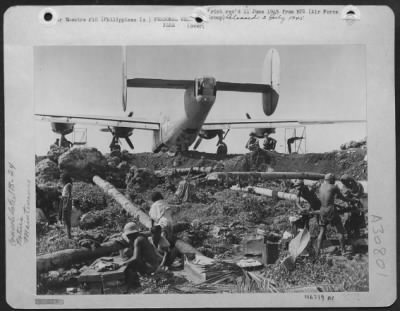 Consolidated > Mechanics in the 13th AAF's Liberator squadrons get their laundry done while they work on the big bombers. Roving Filipino laundry squads armed with brushes and soap supply the "curb service," and it's a welcome change to the veteran "Jungle Air