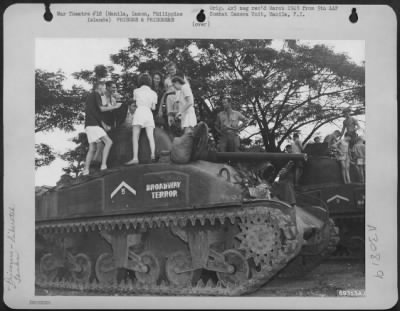 Consolidated > The huge tanks of the conquering G.I.'s caused much excitement among the internees of the Santo Tomas compound in Manila, Luzon, Philippine Islands. Here, a group of "tankers" show off their beauty to several girls and lads. February 1945.