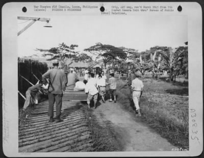 Consolidated > Members of the 1st Cavalry guard Japanese prisoners as they bury the dead at the Santo Tomas University prison camp at Manila, Luzon, Philippine Islands.