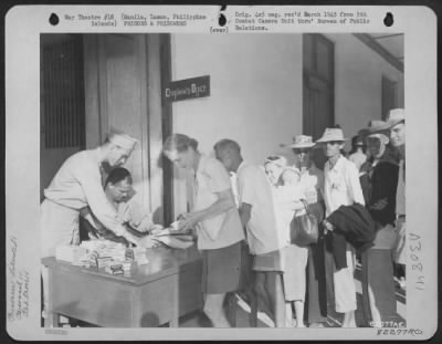 Thumbnail for Consolidated > Prisoners liberated from a prison camp in Manila, Luzon, Philippine Islands, are checked off by Army Lt. Col.  Jack Blocker, Jacksonville, Fla., while Mr. C. Leo Wilhelm of the Red Cross gives out cigarettes and candy.