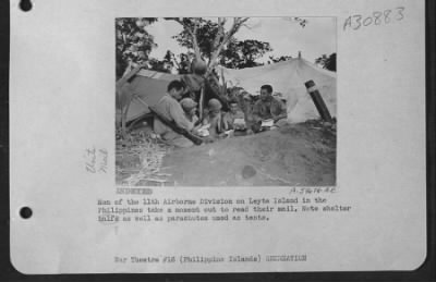 Thumbnail for Consolidated > Men of the 11th Airborne Division on Leyte Island in the Philippines take a moment out to read their mail. Note shelter balfs as well as parachutes used as tents.