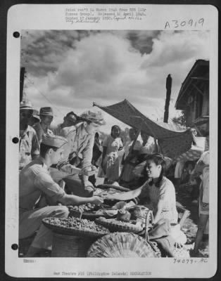 Thumbnail for Consolidated > The sidewalks of Pateros are crowded with venders' stalls at fiesta-time, the celebration of the liberation of the village of Pateros by the 11th Airborne and the 1st Cavalry Divisions. Here a smiling young business woman shows off local delicacies