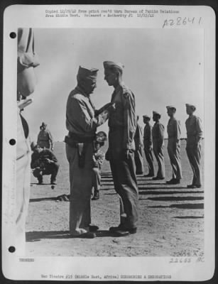 Consolidated > Sgt. John Banco receiving the Purple Heart for wounds received while participating in aerial combat with enemy planes in the Middle East. Lt. Gen. Frank M. Andrews, Commanding General of U.S. Army Forces in the Middle East presented the Medal at an