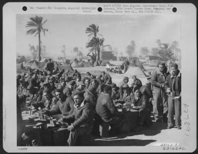 Thumbnail for Consolidated > Algiers, Algeria-Our Air Forces breakfast somewhere in North Africa beside parked trucks and tents pitched among wind-whipped palms. Previous tests in Army's climatic laboratories have determined just what kinds of food, clothing and equipment should