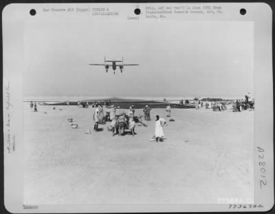 Thumbnail for Consolidated > As natives continue their construction work at the end of runway, a North American B-25 comes in for a landing at Payne Field, Cairo, Egypt.