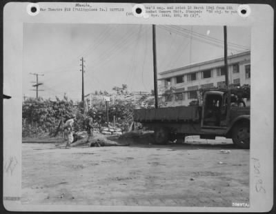 Thumbnail for Consolidated > The sharp tattoo of the Jap "woodpecker" machine gun breaks out, and these two men from the 1st Cavalry dash for cover behind the knocked out Jap truck. A moment before they had killed the Jap shown in the foreground when he made a charge from the