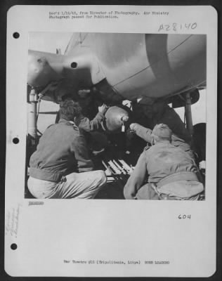 Consolidated > Armorers load bombs into a fighter-bomber on an advanced airfield in Tripolitania, Libya, before a sortie over the enemy line.