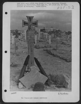 Thumbnail for Consolidated > Anti-aircraft shells propped against the cross of a German grave in a burial ground on the edge of an airfield in Libya.