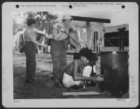 Thumbnail for It's Monday (washday) at a WAC camp somewhere in New Guinea. T/4 Gillie Tanksley of Bokoshe, Oklahoma, hangs up some of the wash while T/4 Berta Hodnett of Notasulga, Alabama, lifts clothes out of the boiler. A native assists in building the fire. - Page 1