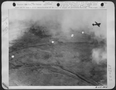 Thumbnail for Consolidated > Here can be seen a vivid demonstration of the various stages of parachutes opening. From right to left: the man closest to the plane has just jumped; the second unopened parachute can be seen clear of his body; the third soldier's parachute has just