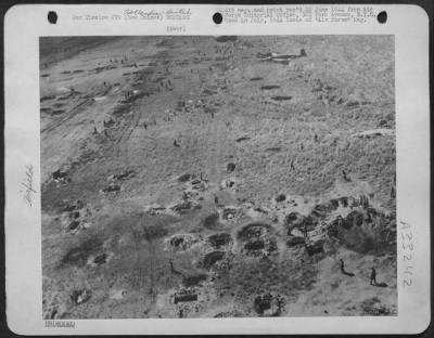 Thumbnail for Consolidated > Ground forces on one of the Hollandia airdromes take a good look at the job of reconstruction they have ahead of them. The huge craters in the foreground and along the runway indicate to thoroughness with which the 5th Air Force softened up Hollandia