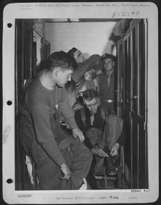 Fighter > ENGLAND--These 8th Air force P-51 Mustang pilots have just returned from a mission escorting the heavy bombers over Germany. The pilots are removing their heated flying clothes in front of their lockers. Lt. Albert M. Koenig, of 1243 Kenwood