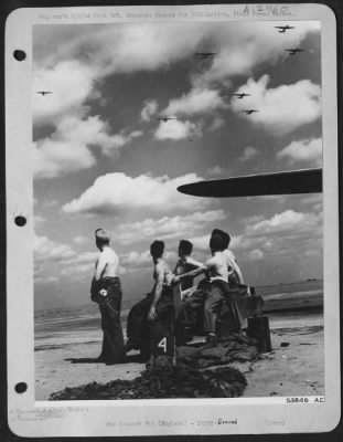 Thumbnail for Ground > Stripped to the waist to enjoy an all-too-rare day of sunshine in England, these mechanics and ground crew members of an 8th AF Consolidated B-24 Liberator base, anxiously examin the formations returning from a bombing mission. Each man watches