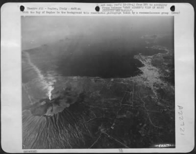 Thumbnail for Consolidated > With the Bay of Naples in the background this remarkable photograph taken by a reconnaissance group of the Northwest African Air Forces, vividly pictures Mount Vesuvius in the left foreground, smoke pouring from its crater. The city of Naples is at