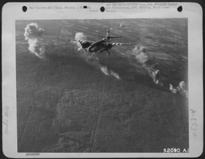 Thumbnail for Caen > A Martin B-26 Marauder of the 9th Air Force, one of the many attacking enemy military objectives is shown heading for home. Smoke billows from a road below by the side of a forest near the battle line at Caen. This successful mission by 9th Air