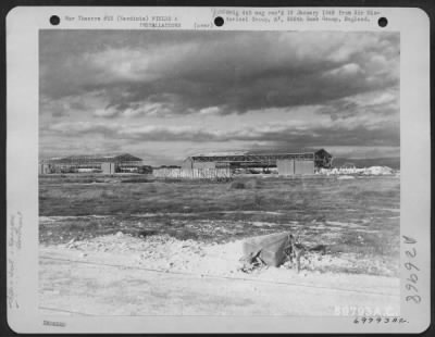 Thumbnail for Consolidated > Northeast view taken from an old asphalt runway showing two hangars with a revetment in the foreground at Elmas, Sardinia. 24 November 1943.