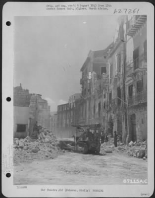 Thumbnail for Consolidated > A bulldozer, operated by a member of the 10th Engineers, clears a debris-littered street in Palermo, Sicily. Note the bomb damaged buildings in the background. July 1943.