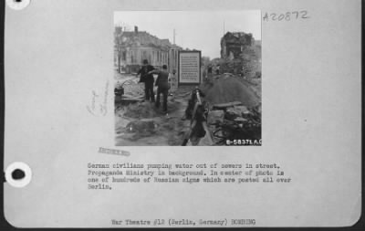 Thumbnail for Consolidated > German Civilians Pumping Water Out Of Sewers In Street.  Propaganda Ministry In Background.  In Center Of Photo Is One Of Hundreds Of Russian Signs Which Are Posted All Over Berlin.